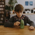 boy playing with green cactus figurine